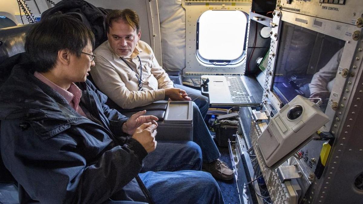 Engineers William Chun, left, and Nino Majurec discuss data at a three-frequency radar control station inside NASA's modified DC-8 jetliner. The radar is capable of giving profiles of cloud structures.
