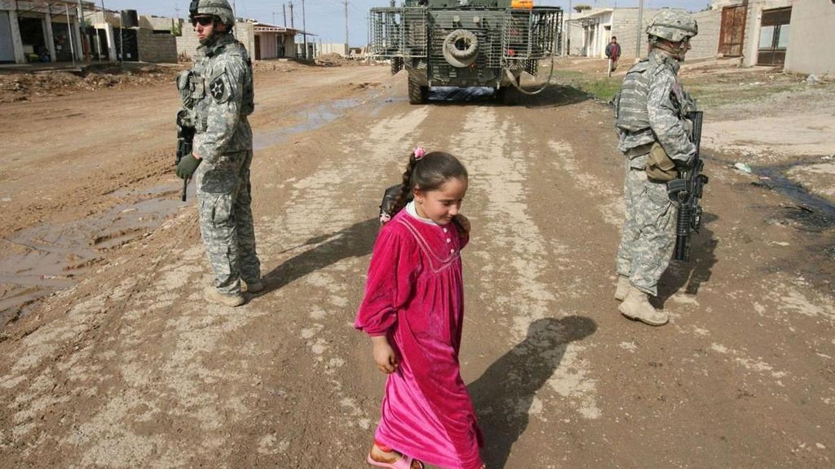 
An Iraqi girl walked past soldiers Sgt. Eric Kramer (left) and Sgt. Christopher Kai from the 3rd Brigade, 2nd Infantry Division as they stood watch on a dirt road in Mosul, Iraq, on Saturday, Oct. 28, 2006. It was the brigade’s second of three deployments to Iraq. The Army this week re-named the headquarters, stirring memories for veterans who served with it at war. (Tony Overman/The Olympian)
