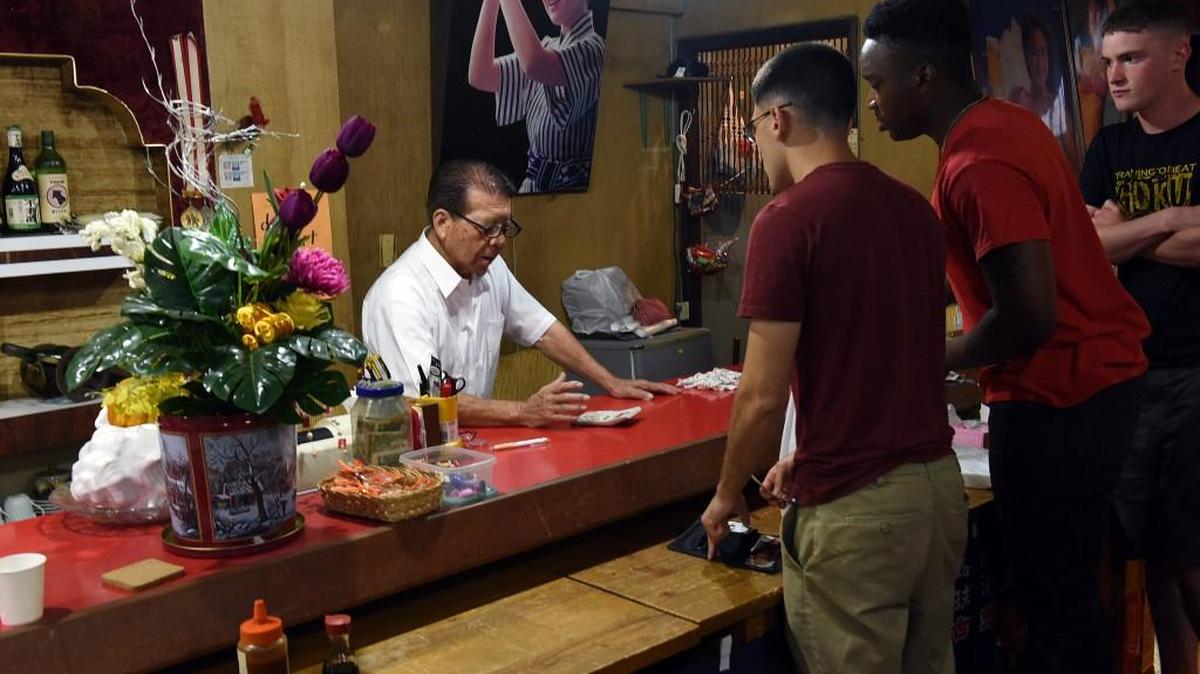 Yoshimasa Shiroma, 85, talks to Marines from Camp Schwab as they settle their bill in late July at Ocean Sushi Restaurant in Henoko, a village known to be friendly to Americans in Okinawa, Japan.