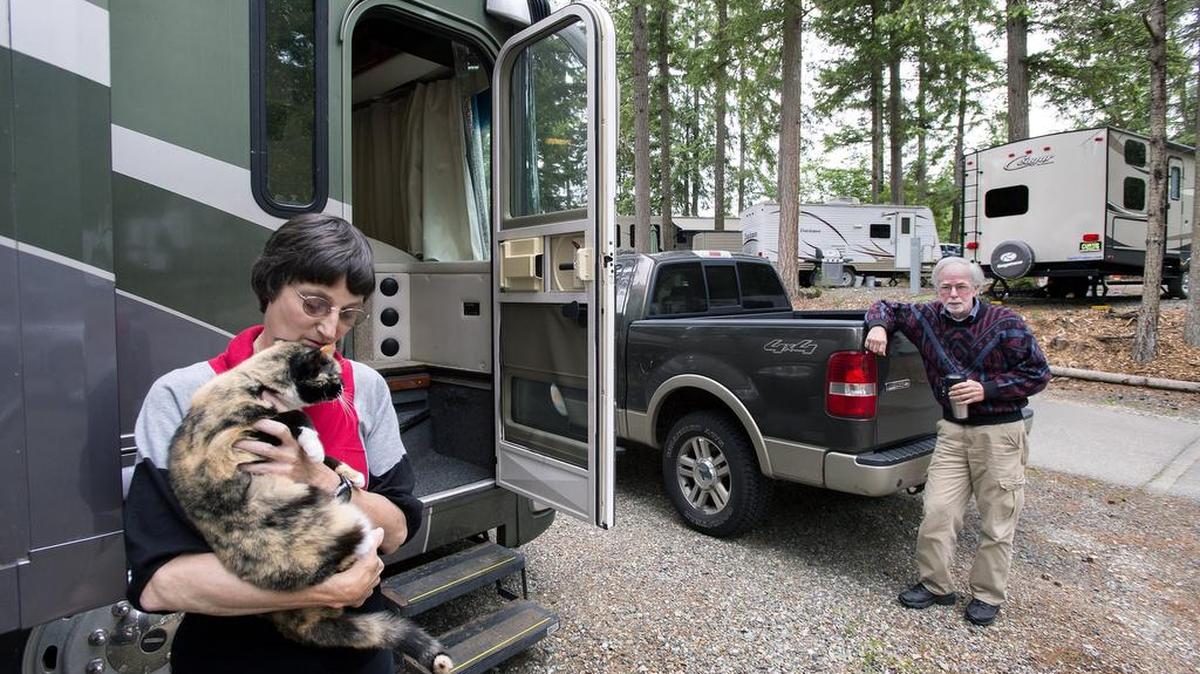 Public Health Service Cmdr. Carol Kirkland nuzzles her cat, Owl Bait, outside her motor home at the Gig Harbor RV Resort as friend Robert Braley, a retired Alaska Air National Guard master sergeant, looks on. Both were recently asked to leave JBLM's Holiday Park campground because their handshake agreement to stay long-term violated Army rules.