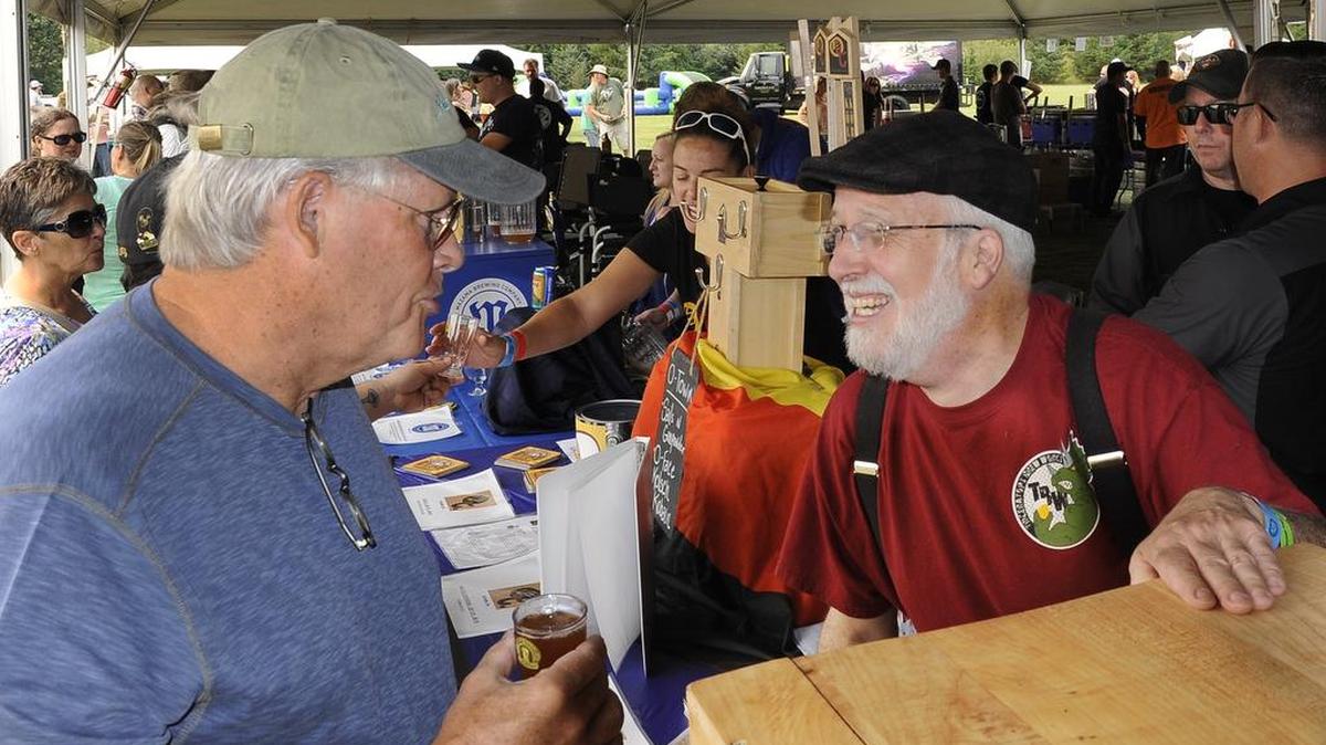 
Operating the serving stand for his son-in-law’s Triceratops Brewing Co., Russ Barton talks beer with attendee Tom McKee at the 2015 Tumwater Artesian Brewfest on Saturday at Tumwater Valley Golf Course.
