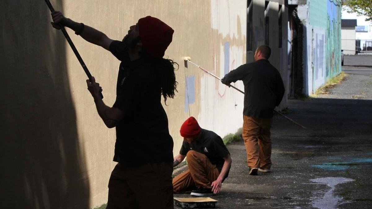 Olympia Downtown Ambassadors (from left) John Parrott, Josh Schwenker and Kyle Olson paint the exterior walls of the burned-out Griswold's Office Supply building in downtown Olympia in 2014.