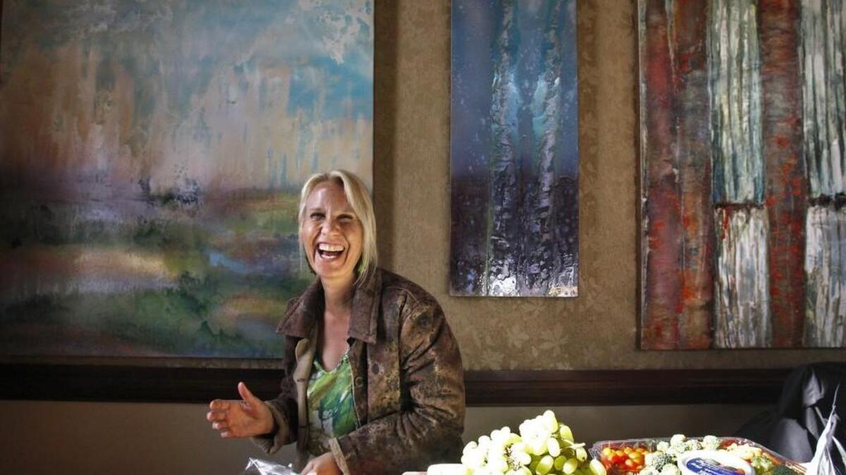 Anna Boatright of Olympia prepares snacks for the oil painting show by her husband, Thomas Boatright, inside the Pioneer Building during the opening day of spring Arts Walk in downtown Olympia on Friday, April 24, 2015. Two of Anna Boatright's paintings are also on display behind her.
