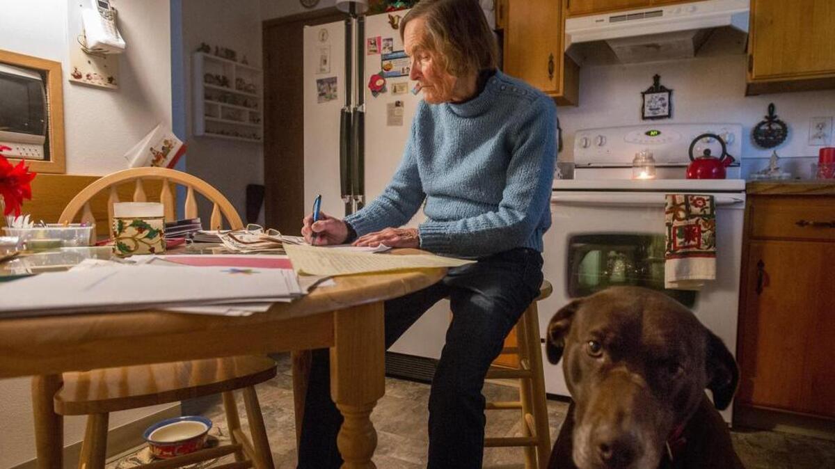Patricia Reynolds of Steilacoom starts a letter to an overseas serviceman or woman. Her dog, Babe, joins her in the kitchen.