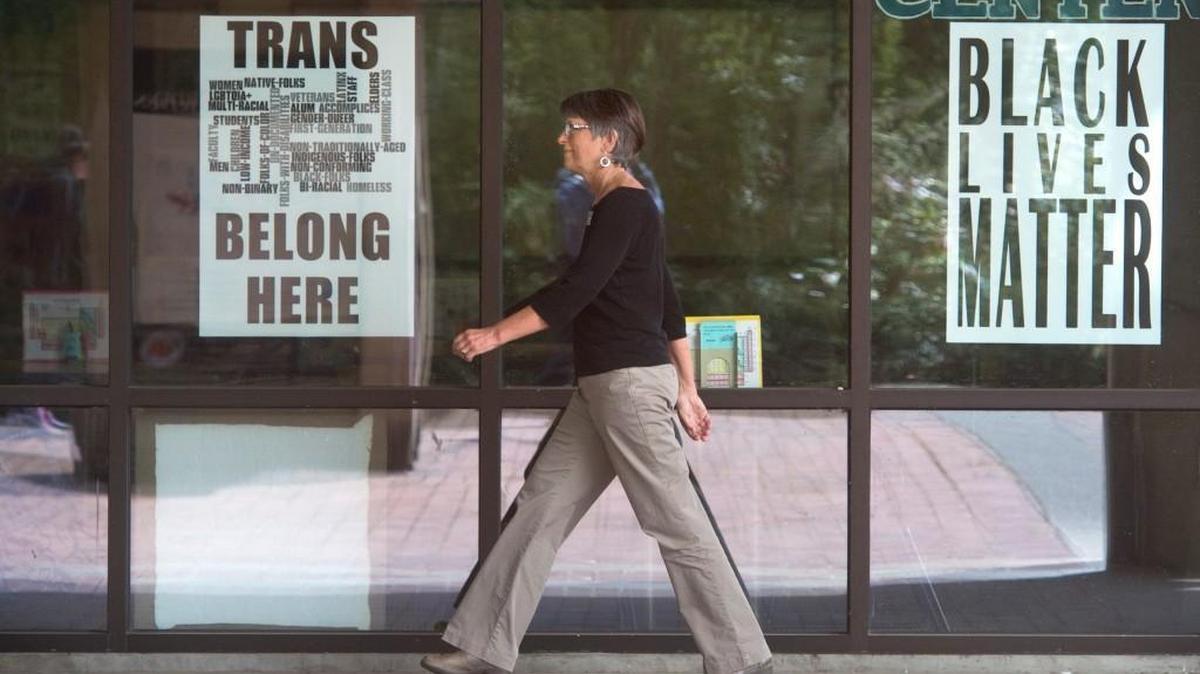 A woman walks past signs posted at The Evergreen State College campus in Olympia on Thursday, June 1, 2017.