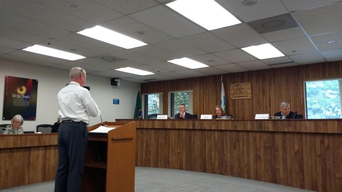 Michael Snodgrass (in white) addresses Thurston County’s Canvassing Board regarding Olympia City Council candidate Lisa Parshley’s voter registration.