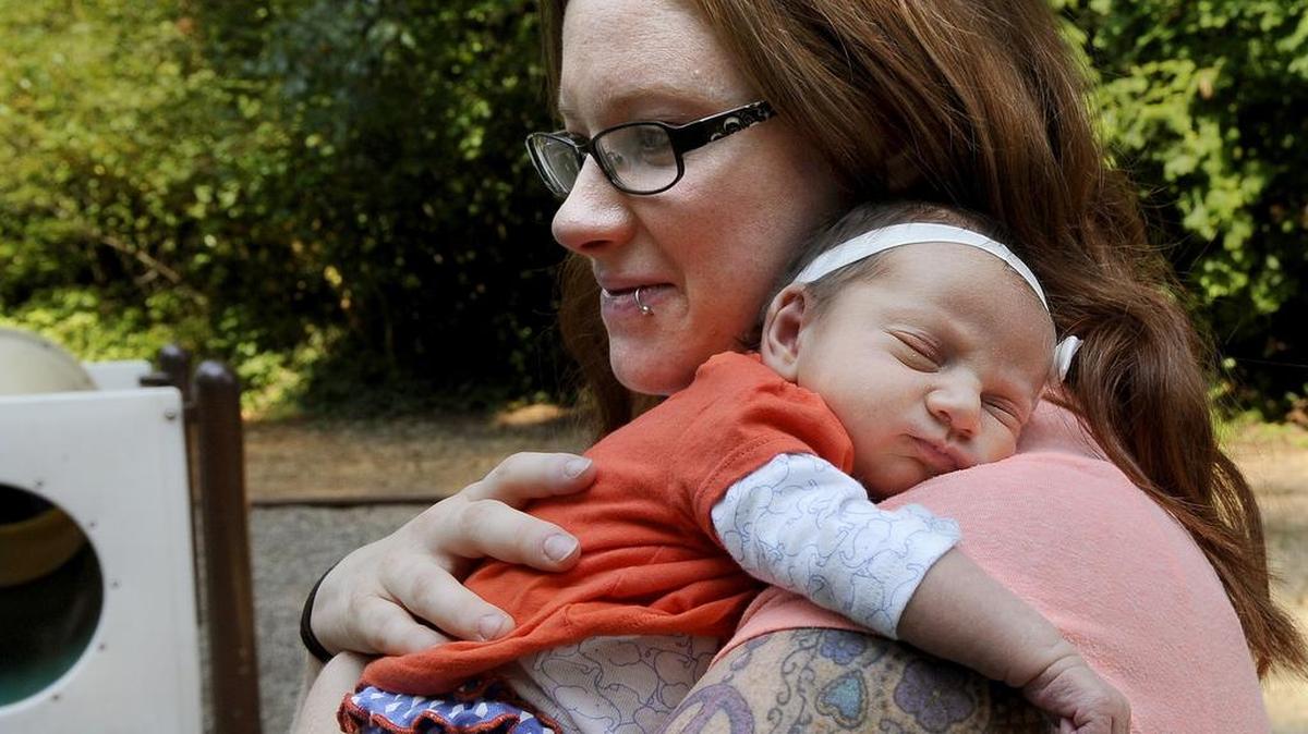 
Melissa Iverson watches her kids at the playground at Reichel Beach near the family’s Clear Lake home Sunday with three-week-old Everleigh Iverson, who was born not only five weeks early in the family car while en route to Providence St. Peter Hospital. 
