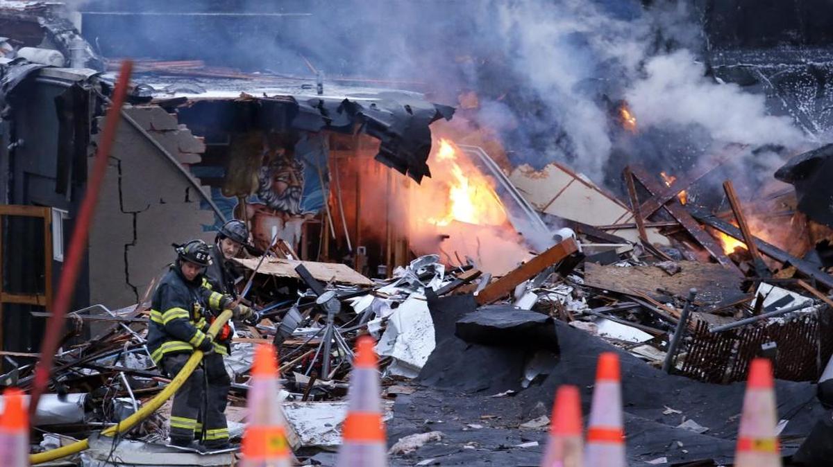 Firefighters move a hose into position as flames burn in the rubble left from an explosion early Wednesday in Seattle. The explosion heavily damaged buildings and injured firefighters.