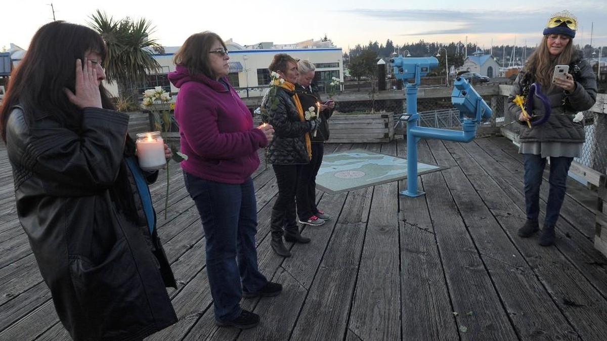 Kari Lee from the Dream Team Angels Rescue (right) conducts a short candlelight service on Percival Landing late Sunday in remembrance of 19 dogs that perished in a January 5th fire at an animal-rescue shelter in Tumwater.
