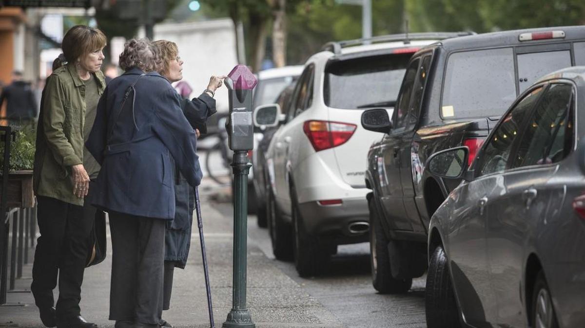 Linda Davis (left) of Sherman Oaks, California, and Denise Warren (right) of San Diego try to figure out how to pay for parking on Fourth Avenue in downtown Olympia while visiting for lunch.