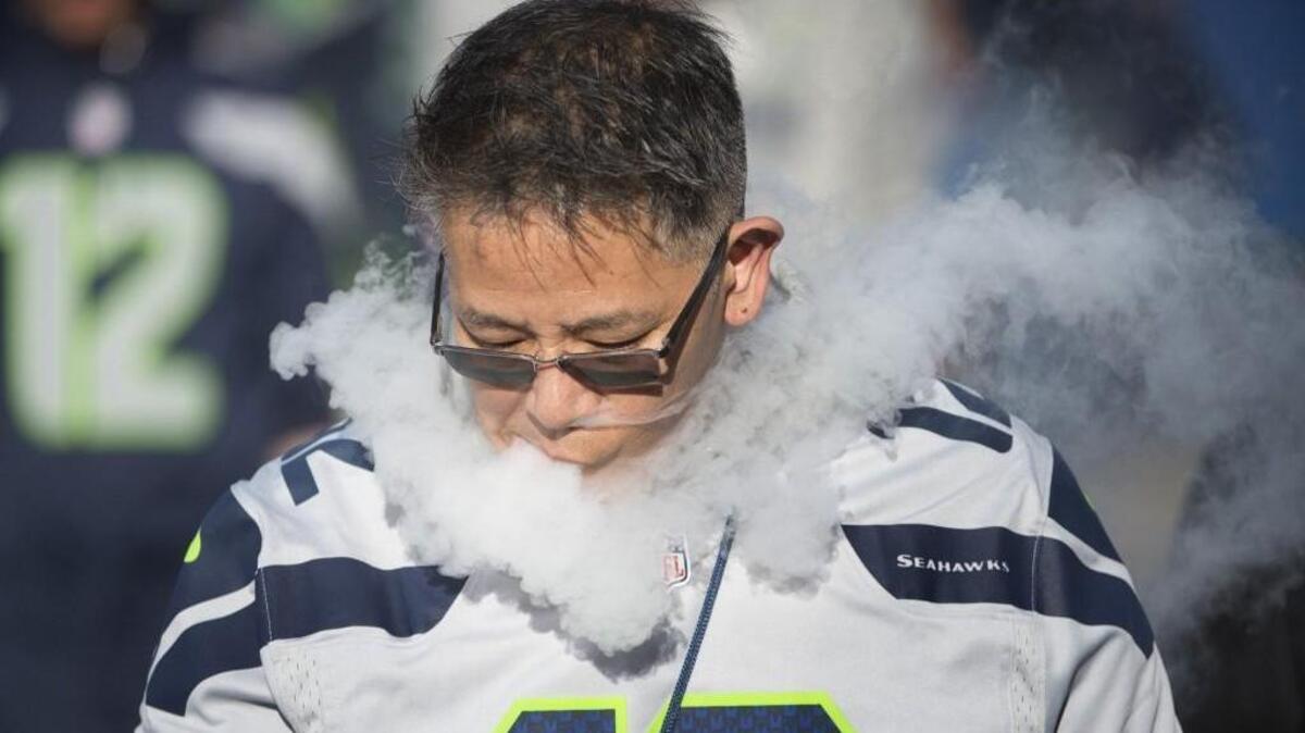 A Seahawks fan lets out a puff of vapor as he walks outside CenturyLink Field before the Monday Night Football game against the Detroit Lions at in Seattle on Oct. 5, 2015.