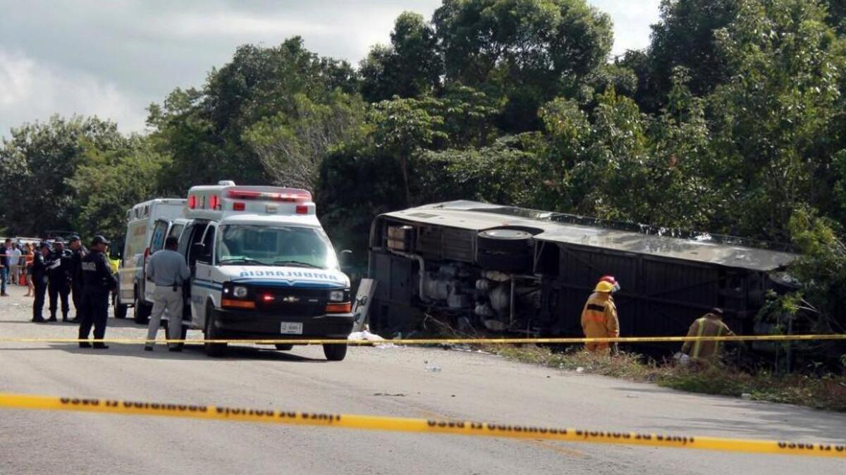 An ambulance sits parked next to an overturned bus in Mahahual, Quintana Roo state, Mexico, on Tuesday. The bus carrying cruise ship passengers to the Mayan ruins at Chacchoben in eastern Mexico flipped over on a highway early Tuesday.