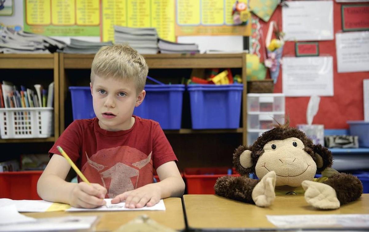 Richard Gordon Elementary School second grade student Dane Menge, 8, thinks about what he is going to write in a letter to student Makoa Saffery who is suffering from cancer. The monkey in the chair next to him is where Saffery sits in class.