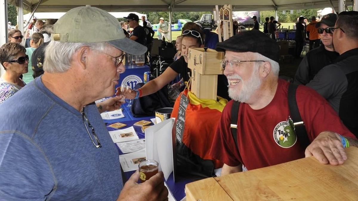 Operating the serving stand for his son-in-law’s Triceratops Brewing Company Russ Barton talks beer with attendee Tom McKee at the 2015 Tumwater Artesian Brewfest Saturday at Tumwater Valley Golf Course.