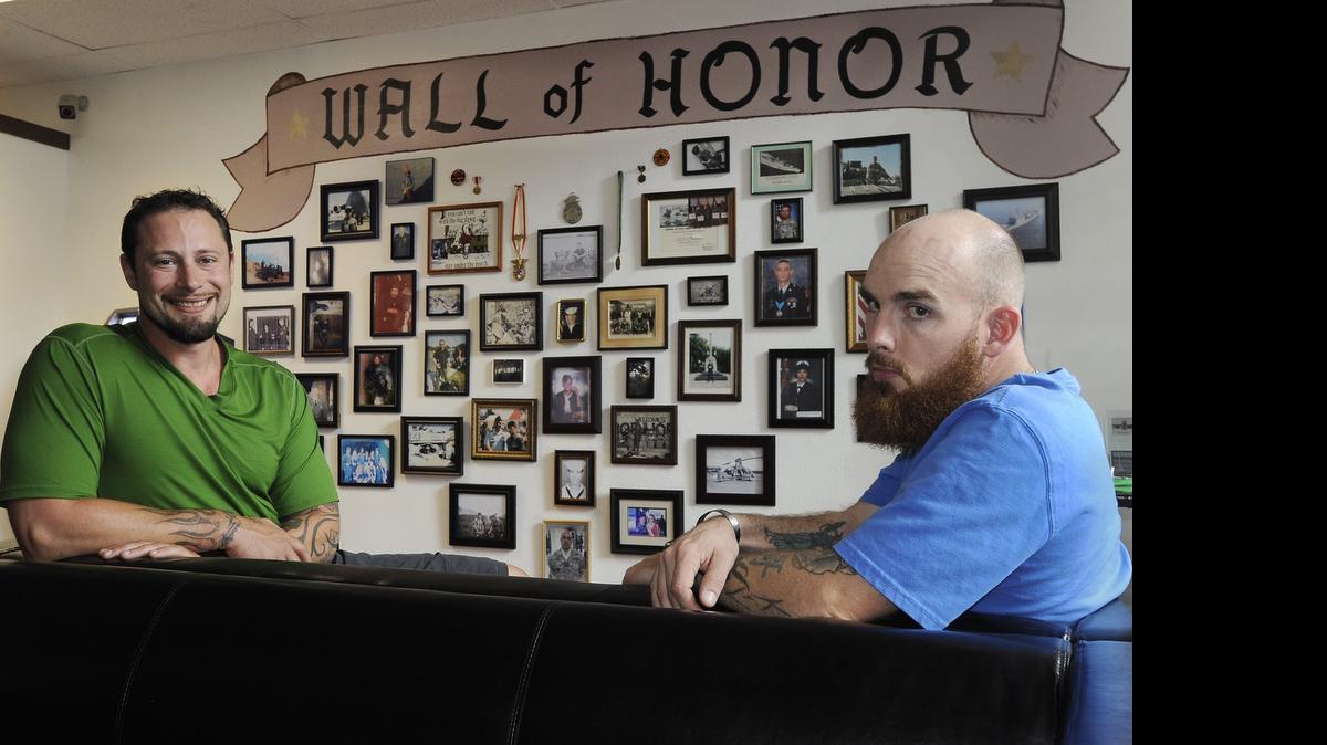 
With a wall  covered with photos of servicemen and women displayed  in their Olympia office at 322 Fourth Ave. on Wednesday, veterans Dante Cammarata (left) and Andrew Collins hope their organization will help support their comrades battling post-traumatic stress disorder. Teaming up with a South Sound medical marijuana provider,  the group has planned a July 22 march to the Capitol. 
