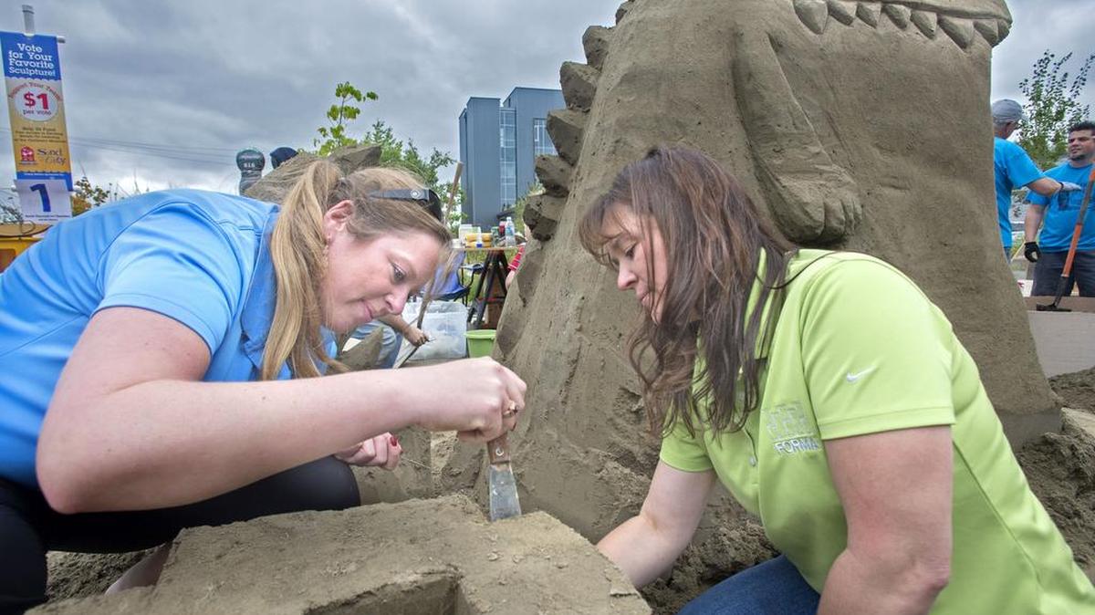 
Forma Construction employees Kim Frazier, left, and Tina Martin work Friday on Erik, a company mascot sand sculpture, during the 15th annual Sand in the City at Hands On Children’s Museum in Olympia. Fifty to 100 volunteers were pounding up the forms for the sculptures.
