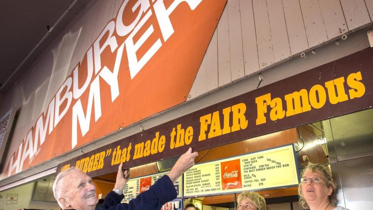 
From left, Rick Myers, 84, has retired now that the state fair in Puyallup is over. Myers began taking orders at his father’s Hamburger Myers stand when he was 7 years old. He and his wife, Joan, sold the 100-year-old business to manager Sheri DeVore. Longtime cook Sue Fox also was on hand when Rick began taking down the sign Monday. Don’t worry, DeVore says, “it will be the same burgers.” 
