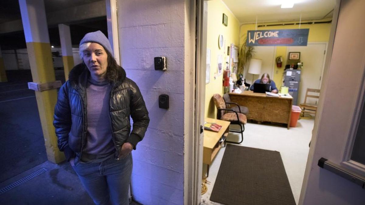 Shelter director Meg Martin waits at the entrance to greet guests as they arrive at the Interfaith Works Emergency Overnight Shelter at First Christian Church in downtown Olympia. Shelter staffer Dave Wade waits inside to register guests. The center celebrates its one-year anniversary this month.