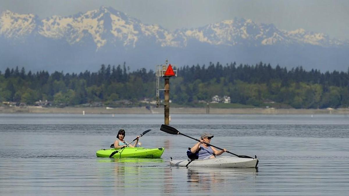 Enjoying a summer like April afternoon with the majestic Olympic range as a backdrop kayakers Bonnie Whitaker (left) and Kelly Millett glide into the Swantown Marina docks as stellar and even hot temperatures for this time of year are forecasted around the region.