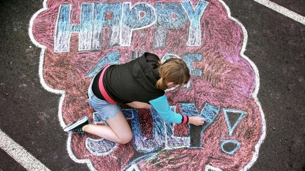 Ariona Yates of Fort Hood, Texas, creates a chalk art display as she and friends wait for the City of Lacey's annual July 3rd fireworks in 2014.