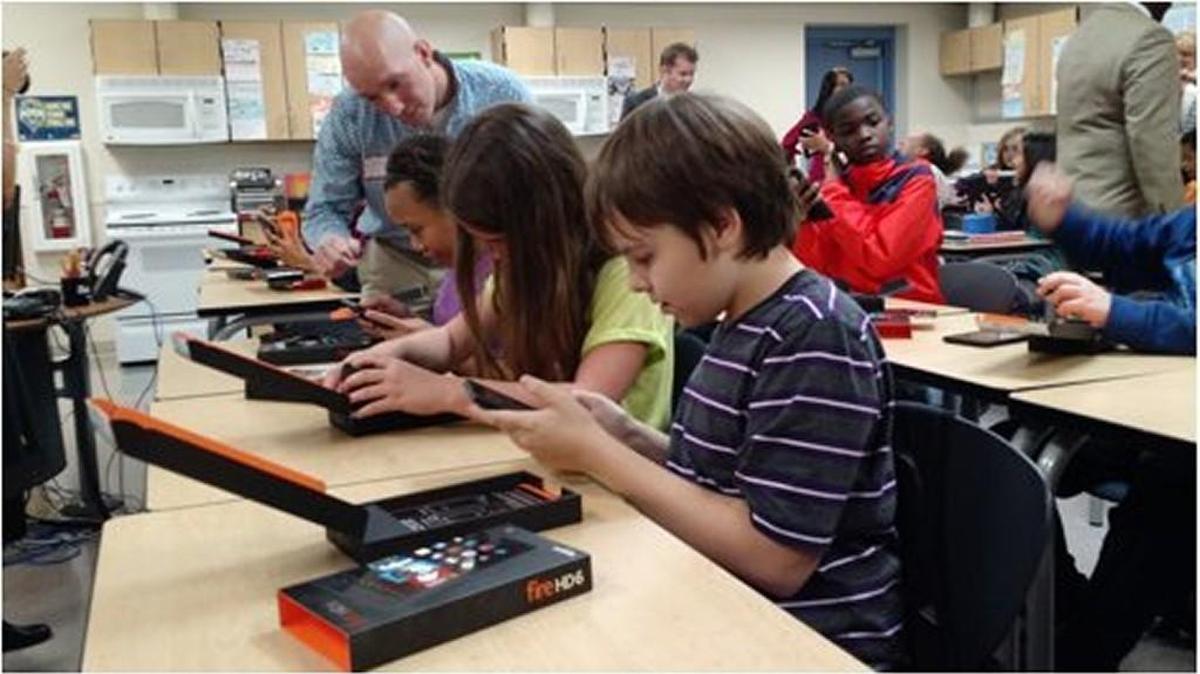 
Students at Pioneer Middle School show off their new Kindle devices Monday to Greg Zielinski of Amazon’s DuPont fulfillment center. 

