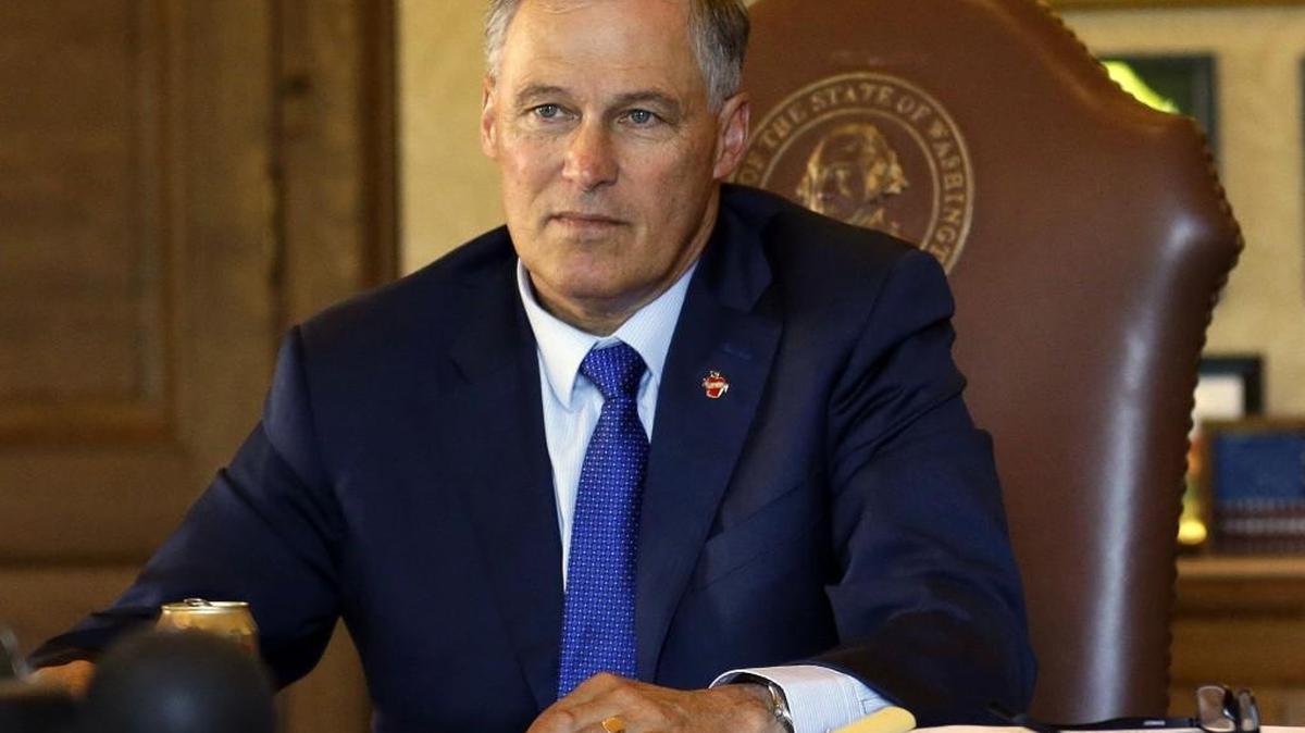 FILE -- In this June 30, 2017, file photo, Washington Gov. Jay Inslee, left, listens as he meets with staff members in his office as they review the state operating budget passed by the Legislature earlier in the day at the Capitol. On Monday, Inslee announced major changes at the Department of Licensing to help protect immigrants’ personal information.