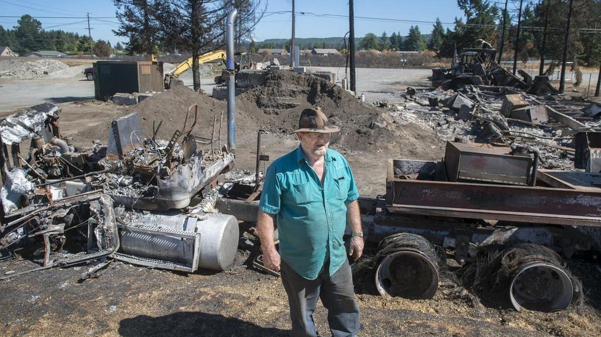 Aaron Lee of Lake Stevens surveys the tractor-trailers and equipment destroyed by the Scatter Creek Fire at T-Jag's Landscape Supply. On Friday, Lee, a retired truck driver, and his family brought a truckload of supplies to help the business rebuild.