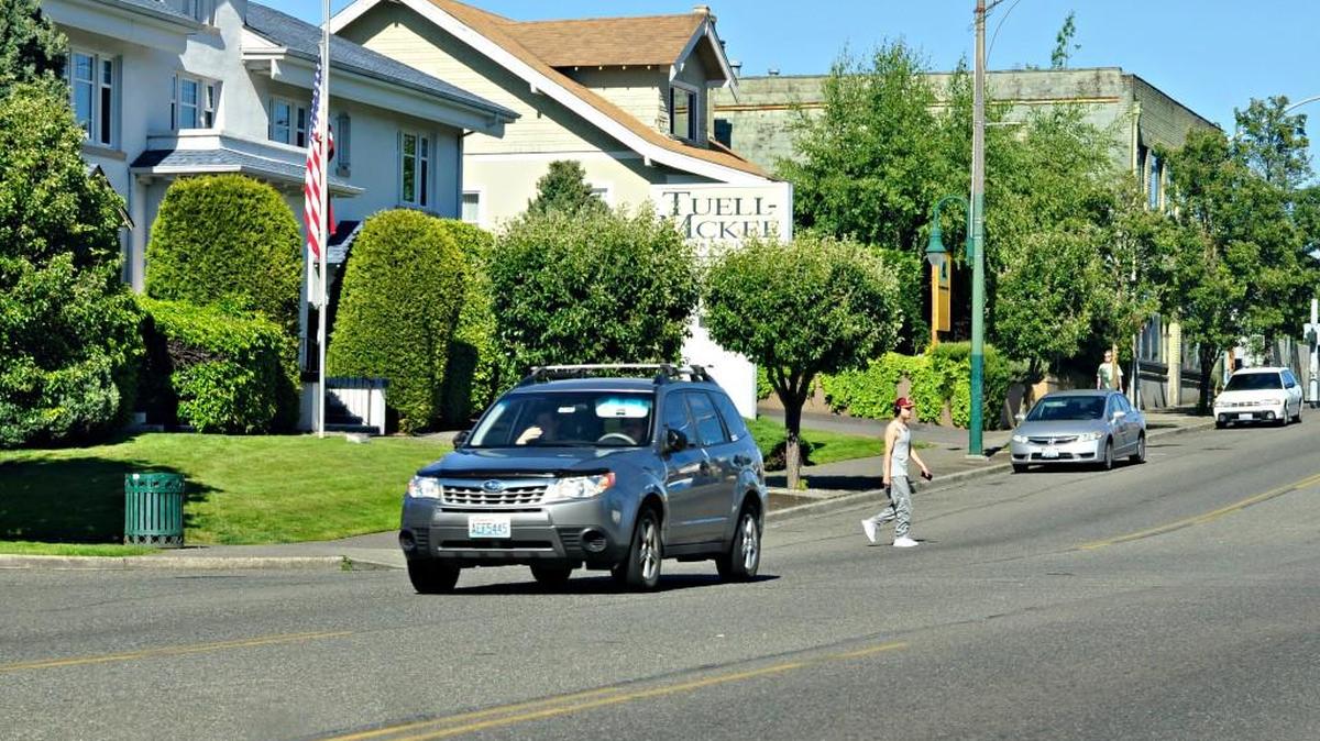A pedestrian uses an unmarked crosswalk to cross Sixth Avenue at South Trafton Street in Tacoma on Friday.