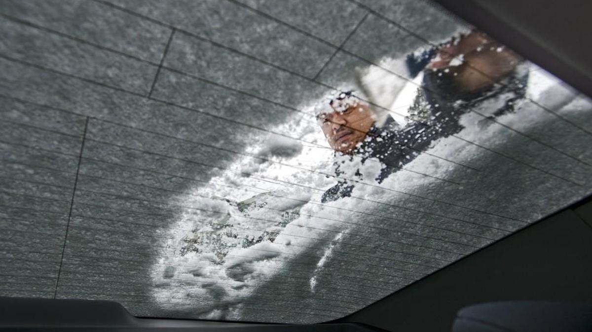 John Scanlan scrapes snow off his car window in South Tacoma in 2014.