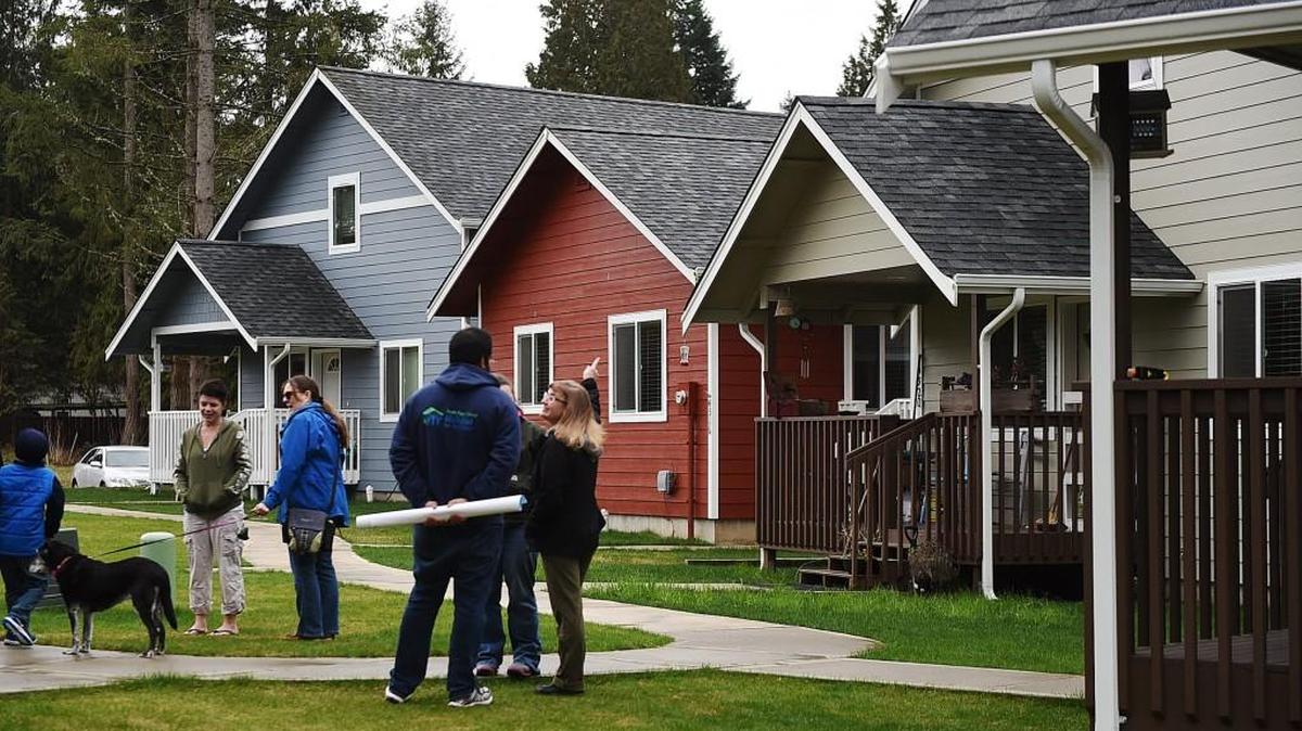 Guests and residents chat in courtyard area after South Puget Sound Habitat for Humanity held a ceremony at its new Lacey area neighborhood, Deyoe Vista.