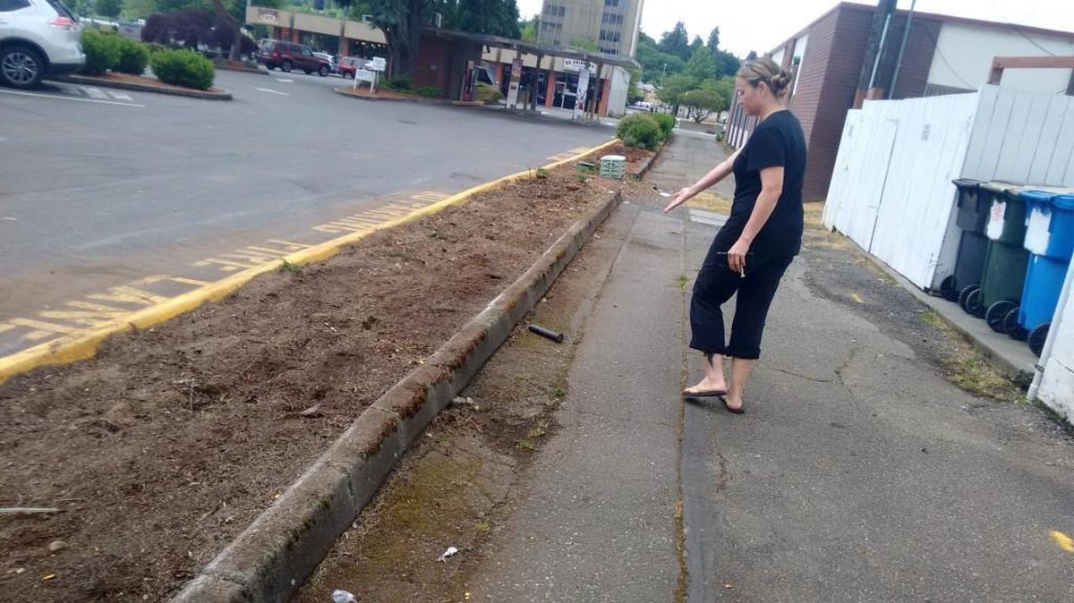 Lisa Scott Owen shows where landscapers removed an herb garden next to The Mark restaurant in downtown Olympia.