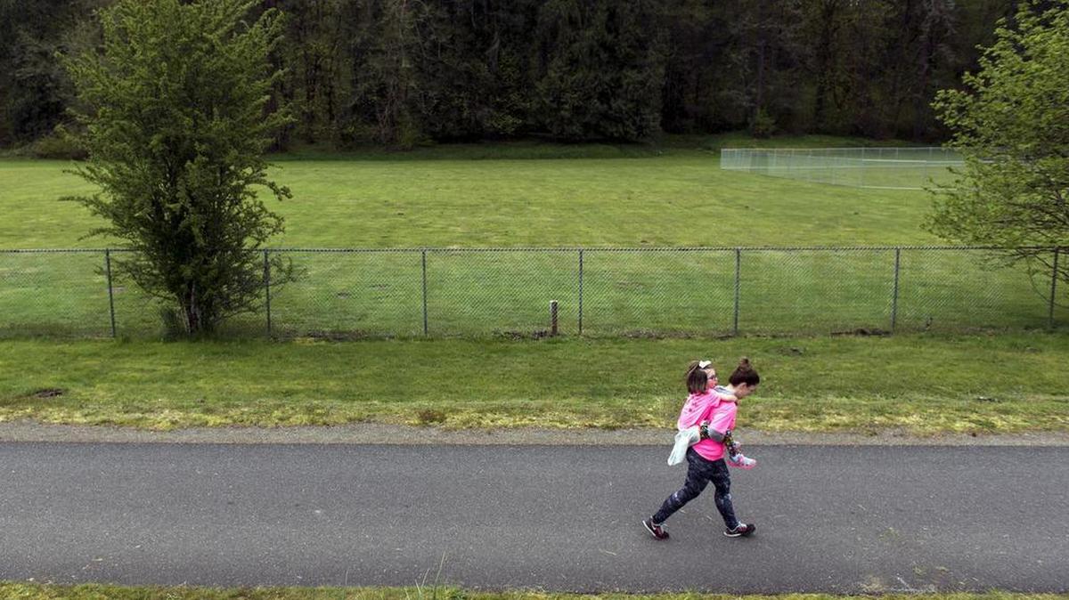 A woman carries a child along the Yelm-Tenino Trail as they near the finish line of the Raise for Rowyn 5K and 10K in Tenino in 2017.