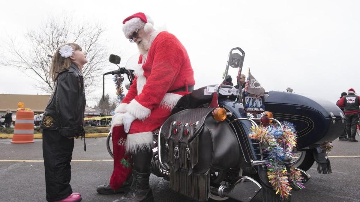 Anna Johnston, 5, of Olympia, tells her Christmas wishes to "Santa Joe" Sullivan, co-founder of the Olympia Toy Run, as they wait for the start of the 2016 event at the South Sound Center. This year’s Toy Run is Saturday.