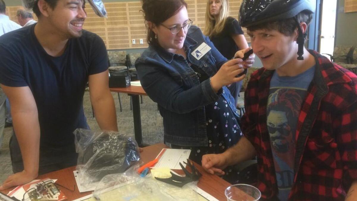 Michelle Swanson, senior program specialist for the city of Olympia, adjusts bike helmets for Alex Clark, right, and Jonathan Gottlieb during an informational open house about bike corridors Thursday at City Hall. Free bike helmets are available to the community at City Hall while supplies last, Swanson said.