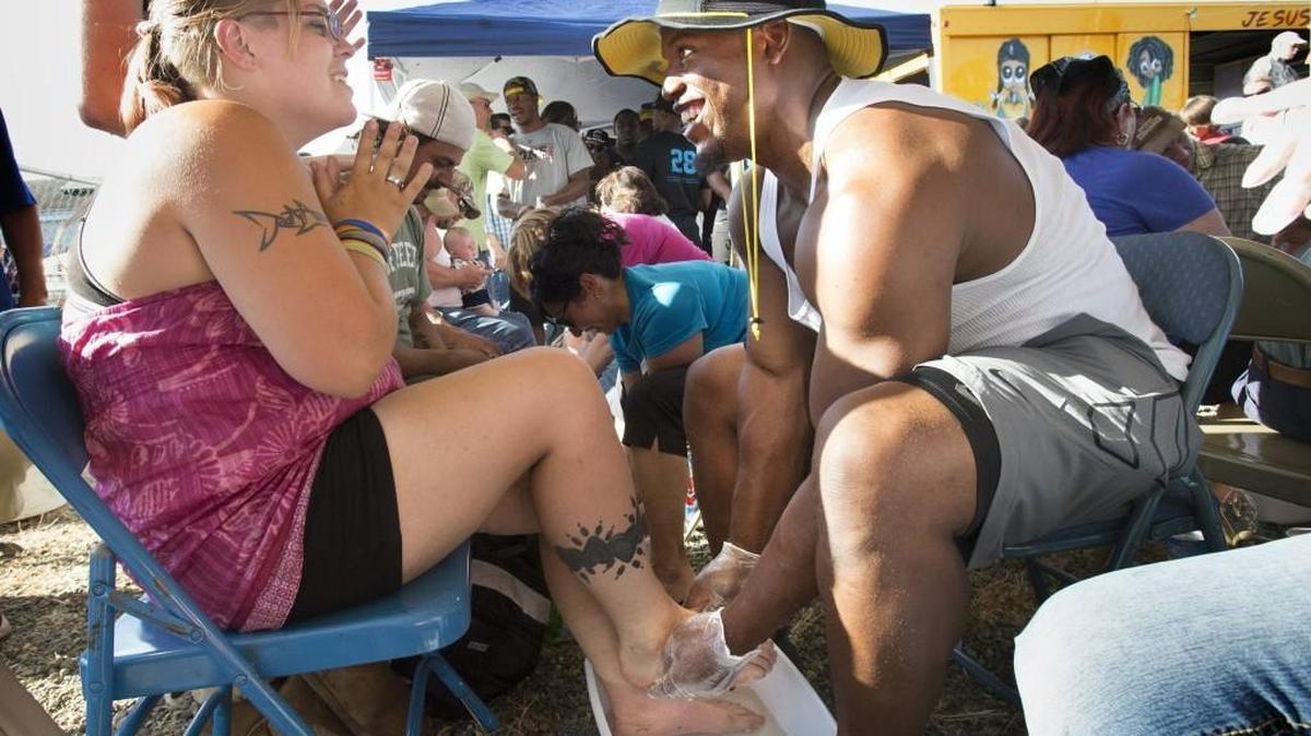 Carolina Panthers running back Jonathan Stewart — a Timberline High graduate — chats with Robin Wills of Tumwater as he washes her feet during the weekly City Gates Ministries outreach in downtown Olympia on July 1. Stewart was joined by fellow NFL players and friends who also volunteered for the event, which gave away 500 pairs of new shoes.