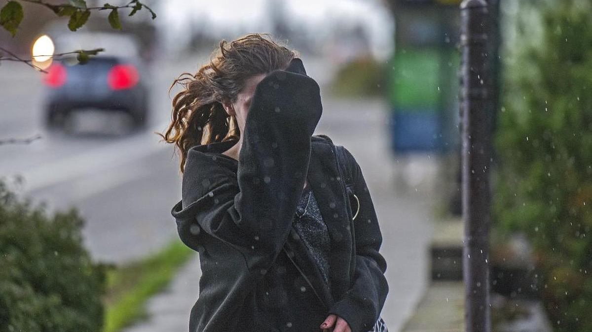 FILE PHOTO: A young woman covers her face as winds and rain pelt her earlier this month. Olympia had about 12 inches of rain fall this October.