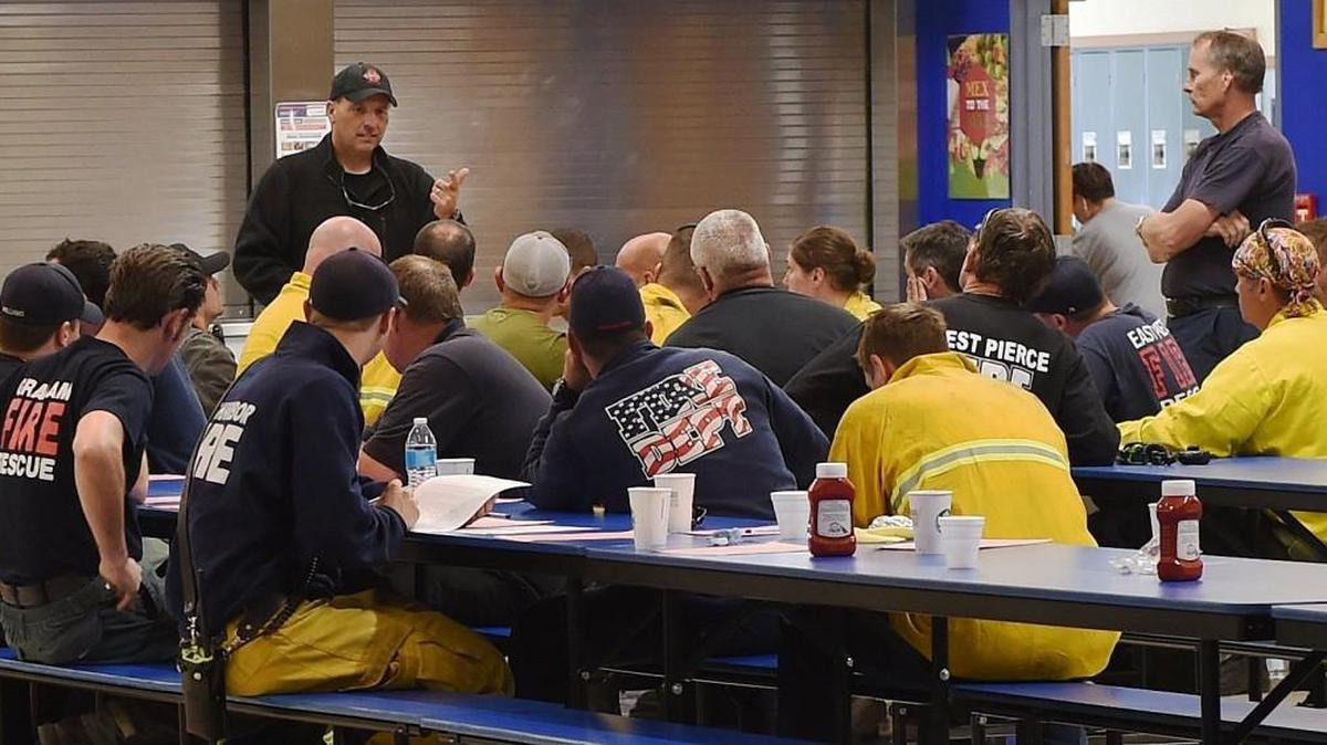 Fire responders hold a Wednesday morning briefing at Rochester High School after Tuesday's 400+ acre brush fire was put under control.