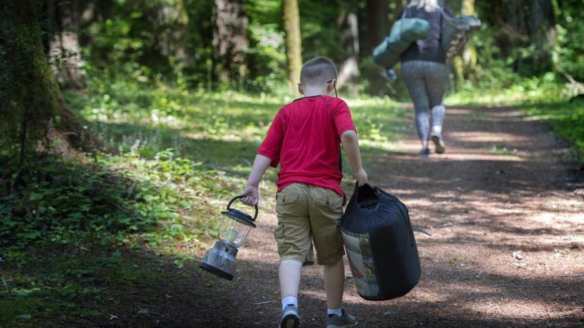 Jacob Turner, 7, follows his mom, Kelly to find a place to pitch a tent at the Great American Backyard Campout in Olympia’s Priest Point Park on Saturday.