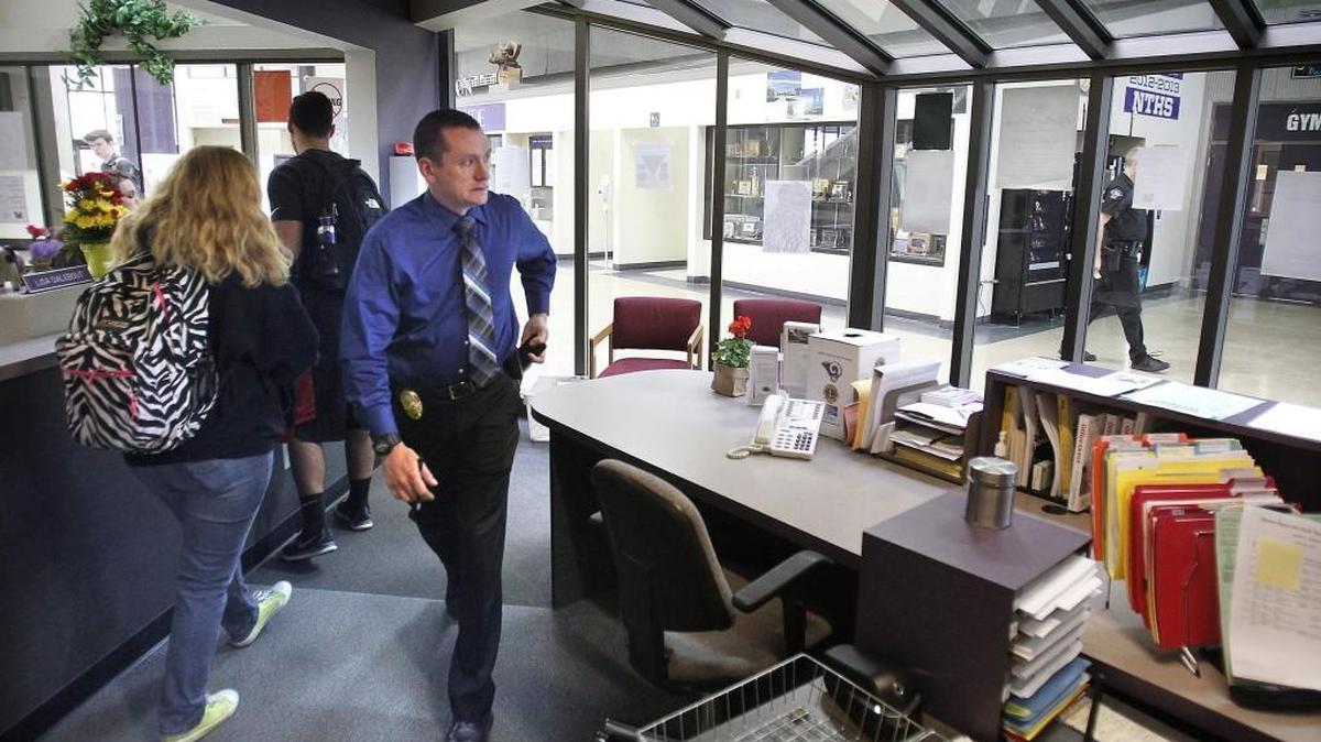 A Lacey police detective passes through the office at North Thurston High School as a school resource officer walks the hallway on Thursday, April 30, 2015.