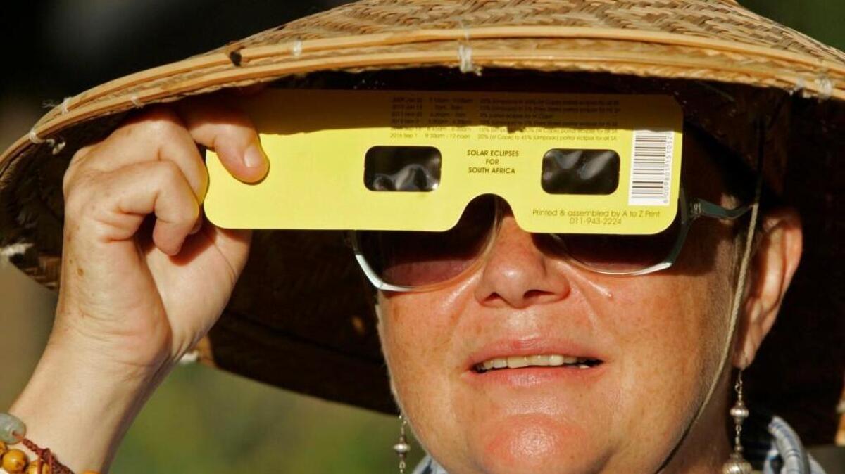 A woman views a solar eclipse through specially-designed viewing glasses. Amateur astronomers and eclipse enthusiasts Jerry Eber and Day Jackson will talk about how to view the eclipse safely on Tuesday evening at the Olympia Timberland Library.