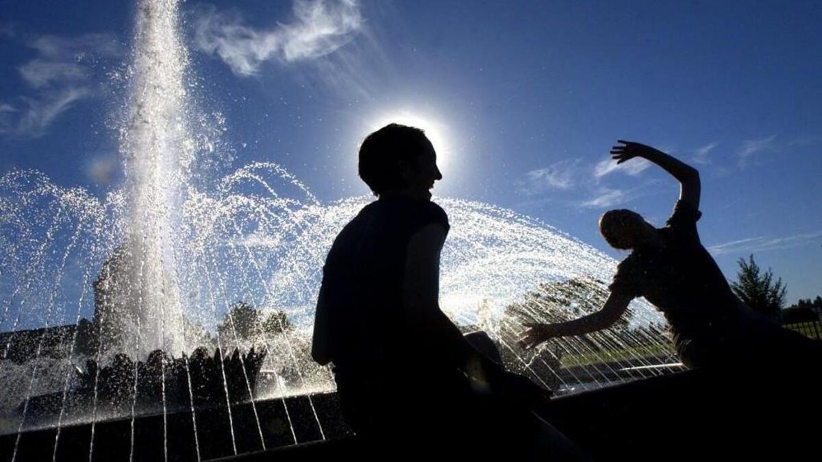 Leanne Laux-Bachard (left) and April MacKay, both of Seattle, take a break from the heat by dipping their hands and feet into Tivoli Fountain on the Capitol campus in this undated file photo.