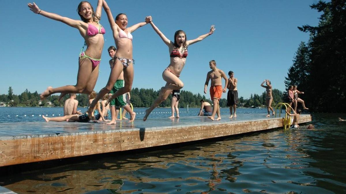 Swimmers strike a midair pose at Long Lake Park in Lacey. Low water visibility prompted a temporary closure of the beach and swimming area starting Tuesday.