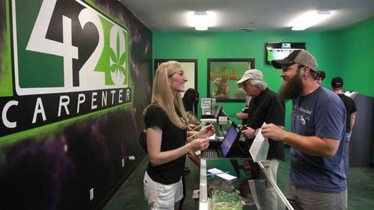 FILE PHOTO: A customer smiles as he completes his purchase of a glass pipe during the first day of recreational marijuana sales in Thurston County at the 420 Carpenter marijuana store east of Lacey in 2014. The Thurston County Commissioners will hold a public hearing on Tuesday to get feedback on proposed permanent zoning regulations for marijuana growers, processors and retailers in unincorporated areas of the county.
