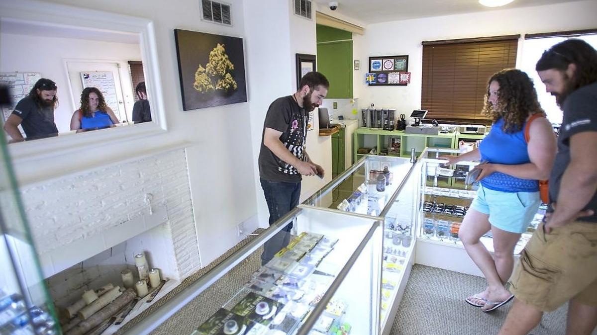 Danny Garcia (left) of Lacey helps customers Susan and Shawn Wheten of Manitou Beach, Saskatchewan, at A Bud and Leaf recreational marijuana store on Lilly Road in Olympia on Wednesday, June 24, 2015.