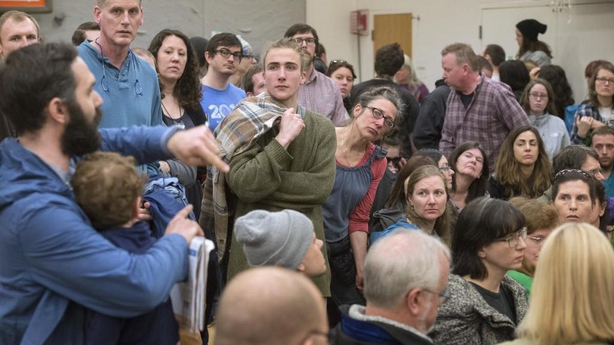 Democratic Party caucus participants listen to Max DeJarnatt, holding his son, Orson, left, of Olympia during the caucus at Madison Elementary School in Olympia on Saturday.