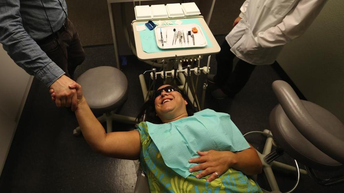 Natasha Fecteau shakes hands with one of her dentists while getting three fillings at Comfort Dental in Tacoma, which takes Medicaid patients.