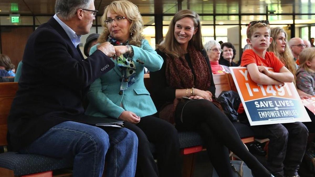 Gov. Jay Inslee and former Arizona congresswoman Gabrielle Giffords fist-bump Saturday at a rally with supporters of Initiative 1491 at First United Methodist Church in Seattle. The initiative would allow families and law enforcement to petition a court to suspend a person’s access to firearms if they are deemed a danger to themselves or others. Giffords, who in 2011 was severely injured in a mass shooting near Tucson, has worked to promote gun-control legislation.