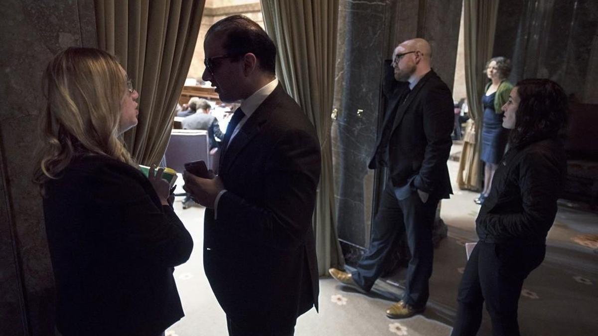 Sen. Cyrus Habib, D-Bellevue, talks with a staff member in the wings of the Senate Chamber during the final day of the regular legislative session in Olympia on Thursday.