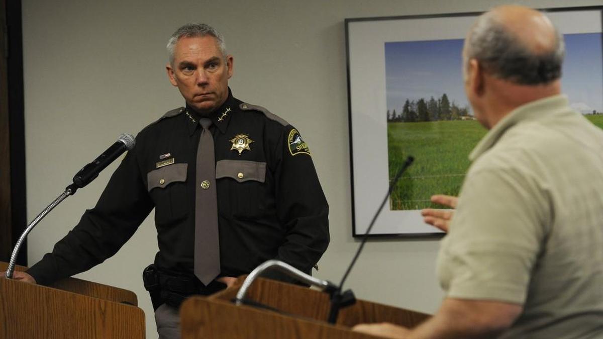 Thurston County Sheriff John Snaza answers a question posed by resident Jon Pettit (right) during Monday’s public hearing on the county’s 2016 budget.