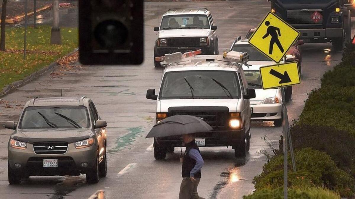 During a recent rain shower, a pedestrian trots across Capitol Way near 14th St. Heavier than usual rains have prompted the National Weather Service in Seattle to issue a flood watch for Thurston, Lewis and Grays Harbor counties. Officials also issued a warning about potential landslides throughout Western Washington.